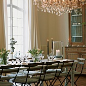 Frühlingshaft gedeckter Esstisch mit Tulpen und antiker Geschirrschrank im Esszimmer mit raumhohen Fenstern