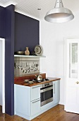 Elegante Miniküche mit hellblauen Schränken und Holzarbeitsplatte in einer dunkelblauen Wandnische
