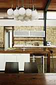 Zeitgenössische Kugelleuchte über dem Esstisch einer modernen Holzküche mit rustikaler Natursteinwand