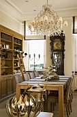 Elegantes Esszimmer mit antiker Standuhr und prunkvollem Kronleuchter über dem Esstisch