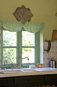Mintgrünes Küchenfenster und Vintagespültheke in einer Landhausküche