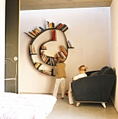 Schlafzimmer mit spiralförmigem Bücherregal an der Wand und zwei davor spielenden Kindern