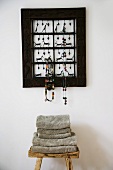Kunstvolle Schmuckgarderobe und rustikaler Hocker mit einem Stapel weicher Handtücher