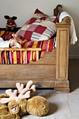 Antikes Kinderbett aus Holz mit farbenfrohem Überwurf, Patchworkkissen und nackten Kinderfüssen