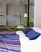 Doppelbett mit blau-violetten Farbakzenten in ruhigem Schlafzimmer