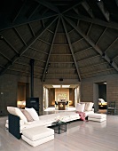 Grosses Sofa in offenem Wohnraum eines Holzhauses mit kuppelfömiger Holzbalkendecke