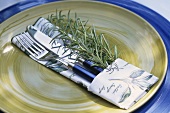 Place-setting with rosemary and herb-patterned fabric napkin