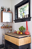 Blick in Küchenecke mit Rolltürschränkchen & rustikaler Ablage aus Holz unter Fenster mit schwarzem Festerrahmen