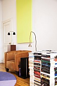 Wohnraum mit Ledersessel und grossem Bücherstapel