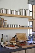 Holzablagen mit Metalldosen & Küchenutensilien über der Küchentheke