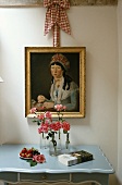 Zimmerausschnitt mit antikem Gemälde über Wandtischchen mit Rosen in Blumenvasen