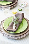 A place setting with a plate in a basket and a napkin decorated with rosemary