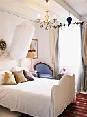 Schlafzimmer mit antikem, weißem Holzbett & Betthimmel