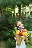 Woman holding plate of fresh vegetables in garden