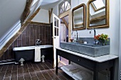 Badezimmer unter Dachschräge mit freistehender Badewanne, länglichem Waschtisch & zwei Spiegeln