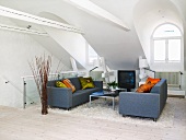 Wohnzimmer im Dachgeschoss mit zwei Sofas, Couchtisch, Fernseher & Flokati-Teppich