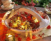 Rose hips and Chinese lanterns in basket with windlights