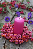 A candle with a wreath of spindle flowers