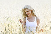 Blonde Frau steht in einem Getreidefeld