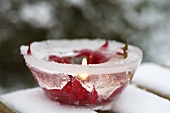 Ice bowl with poinsettia flowers frozen into it and candle