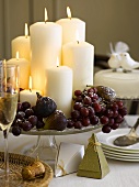 Christmas table decoration with candles, grapes and figs