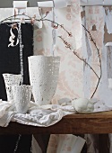 White vases and spring twigs in front of torn wallpaper