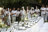 Wedding table in white, wedding guests in the background