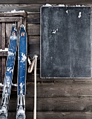 Alte Skier an Bretterwand mit Tafel