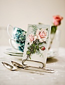 Post card with a picture of a rose on a tea table