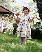 A Girl in a Dress with a Colored Egg and a Basket