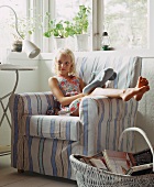 A blonde girl sitting in an armchair