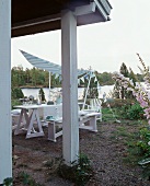 Gedeckter Tisch mit Sonnensegel auf der Gartenterrasse eines Seehauses