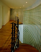 A curved wall made of glass blocks in an illuminated stairway