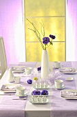 An elegantly laid Easter table with a purple flower in a vase