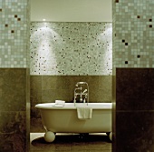 A free-standing, vintage-style bathtub with a mosaic-tiled wall