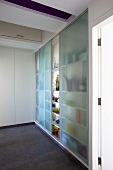 A built-in cupboard full of glasses with sliding doors made of blue grass
