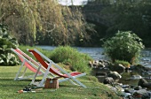 Two loungers and fishing rods by a river