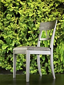 Gray, upholstered dining room chair in front of wallpaper with green plants printed on it