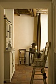 Child's high chair in a passageway with a view into a rustic dining room and side table