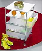 Rolling cabinet with plastic drawers and sneakers on a red carpet