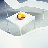 Fruit on a white side table between two loungers