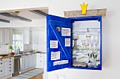 Glasses in an open wall cupboard and view into a white country house kitchen