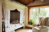 Alkoven und Sessel im ländlichen Dachzimmer mit Fensterfront