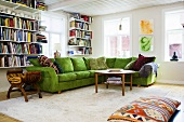 Wohnraumecke mit grünem Sofa und Bücherregalen am Fenster