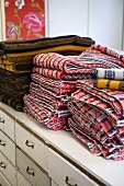 Gestapelte Decken mit Muster weisser Kommode im Vintagelook
