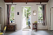 A wood panelled front room in a country house and a girl at a garden door