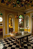 Colourful metal balls hanging from the ceiling in an oriental dining room with a table on a chessboard patterned floor