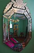 Decorated mirror on a green wall with a reflection