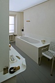 Helles Bad im Designerstil mit umlaufender Ablage und Badewanne auf graulackiertem Holzboden