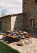 A table laid on a terrace in front of a Mediterranean country house and a stone floor with a herring bone pattern